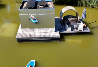 Luftaufnahme eines Hausboots mit Terrasse und Person auf SUP am Domaine des Feuilles, Frankreich.