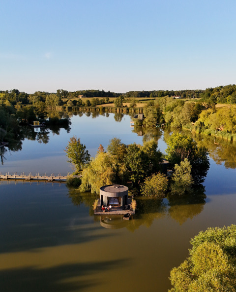 Vista aerea di una cabina sul lago circondata da alberi al Domaine des Feuilles, Auvergne-Rhône-Alpes, Francia.