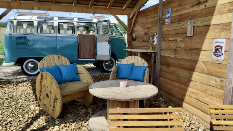 Udendørs siddeområde med genbrugsmøbler ved siden af en klassisk VW van i Domaine des Feuilles, Frankrig.