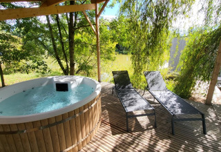 Buitenspa en twee ligzetels onder een pergola bij Domaine des Feuilles, Auvergne-Rhône-Alpes, Frankrijk.