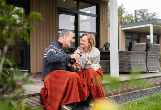 Coppia che si gode un bicchiere di vino avvolta in una coperta alla Vogellodge + hot tub, 't Schuttenbelt, Olanda.
