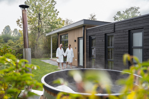 Twee mensen in badjas bij Vogellodge met hottub bij Holiday Resort 't Schuttenbelt in Nederland.
