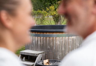 Coppia sfocata in accappatoi bianchi davanti a sauna privata e vasca idromassaggio a ‘t Schuttenbelt, Paesi Bassi.