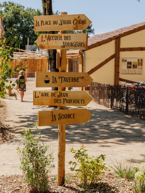 Houten wegwijzers in een vakantiepark in Pays de la Loire, Frankrijk, met richtingaanwijzingen.