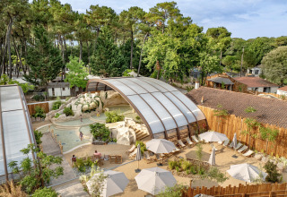 Vue aérienne du Flower Camping Au Bois Des Biches avec piscine couverte et transats en Pays de la Loire, France.