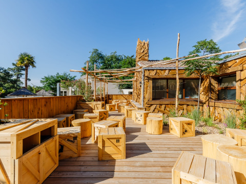 Houten terras met rustieke zitplaatsen bij Flower Camping Au Bois Des Biches, Pays de la Loire, Frankrijk.