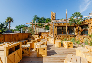 Houten terras met rustieke zitplaatsen bij Flower Camping Au Bois Des Biches, Pays de la Loire, Frankrijk.