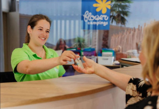 Receptionist consegna una chiave a un ospite al Flower Camping Au Bois Des Biches, Pays de la Loire, Francia.