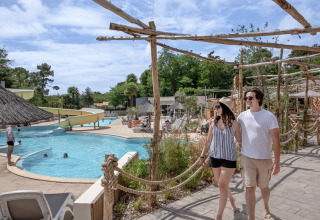 Koppel wandelt langs het zwembad van Flower Camping Au Bois Des Biches in Pays de la Loire, Frankrijk.