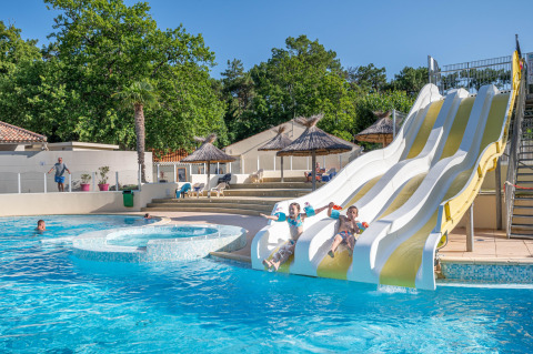 Niños se divierten en los toboganes acuáticos del camping Flower Au Bois Des Biches en Pays de la Loire, Francia.