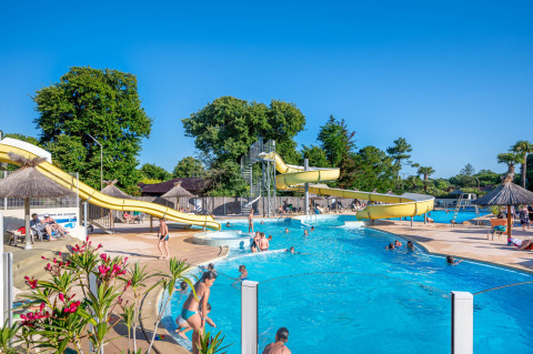 Buitenzwembad met waterglijbanen en bezoekers bij Flower Camping Au Bois Des Biches in Pays de la Loire.