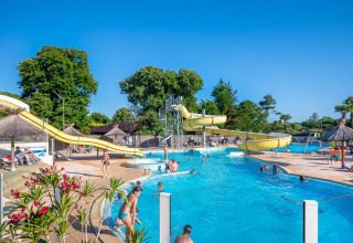 Outdoor pool with waterslides and holidaymakers at Flower Camping Au Bois Des Biches in Pays de la Loire, France.