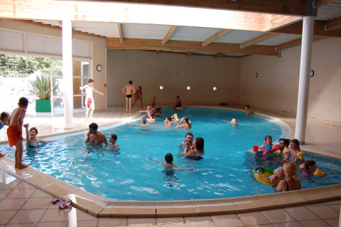 Families and children having fun and relaxing in the indoor pool at Flower Camping Au Bois Des Biches, France.