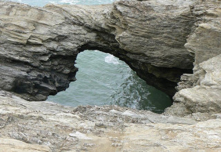 Formación rocosa con arco natural junto al mar cerca de Saint Hilaire de Riez, Pays de la Loire, Francia, sobre el agua.