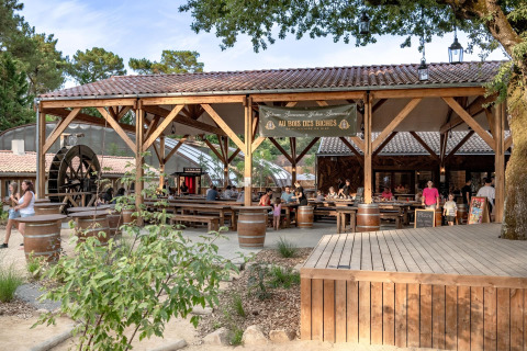 Outdoor dining area at Flower Camping Au Bois Des Biches holiday park with visitors in Pays de la Loire, France.