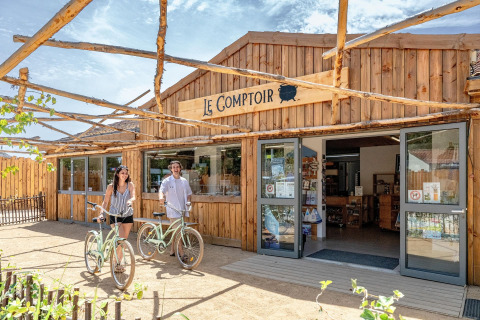 Due persone con biciclette davanti a Le Comptoir presso Flower Camping Au Bois Des Biches, Pays de la Loire, Francia.