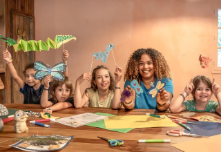 Niños y una adulta hacen manualidades de papel en Flower Camping Au Bois Des Biches en Pays de la Loire, Francia.