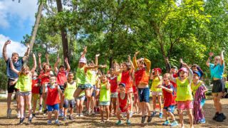 Kinder und Erwachsene springen und spielen gemeinsam im Grünen beim Flower Camping Au Bois Des Biches.