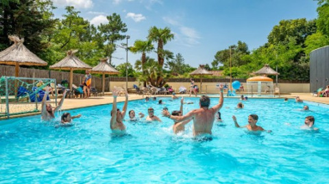 Menschen spielen und entspannen im Pool von Flower Camping Au Bois Des Biches in Pays de la Loire, Frankreich.