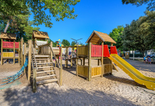 Kinderen spelen op houten speeltuin met glijbaan in Flower Camping Au Bois Des Biches, Pays de la Loire, Frankrijk.