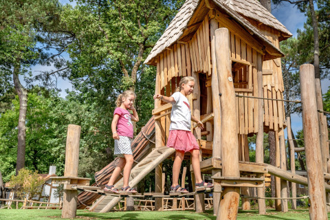Zwei Kinder spielen auf einem Holzspielplatz bei Flower Camping Au Bois Des Biches, Pays de la Loire, Frankreich.