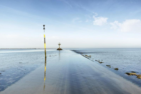 Flooded coastal road with markers at Flower Camping Au Bois Des Biches holiday park in Pays de la Loire, France.