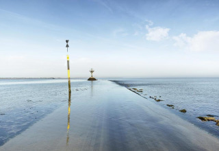Flooded coastal road with markers at Flower Camping Au Bois Des Biches holiday park in Pays de la Loire, France.