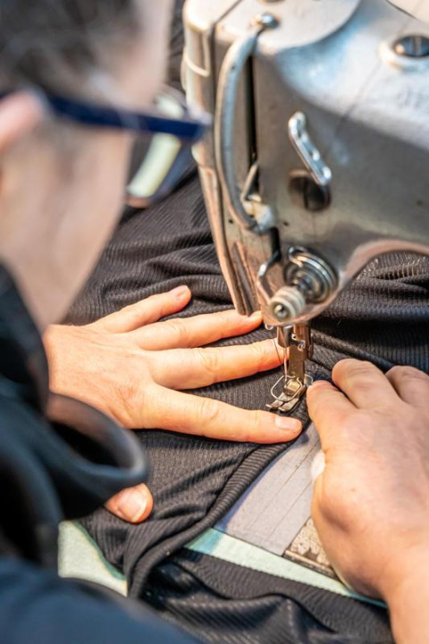 Close-up of a person sewing dark fabric with a sewing machine at Flower Camping Au Bois Des Biches, France.