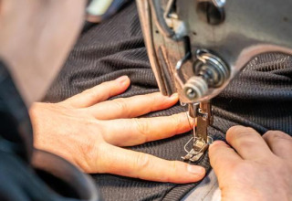 Close-up of a person sewing dark fabric with a sewing machine at Flower Camping Au Bois Des Biches, France.