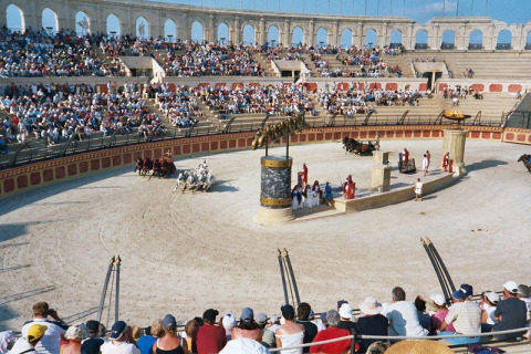 Crowds watch a historical chariot race performance in a recreated Roman amphitheater in Pays de la Loire, France.