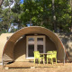 Safari tent Tent Lodge Coco Sweet with deck and green chairs, set on a sunny forest camping site.