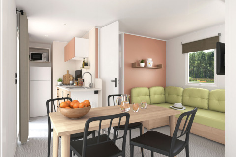 Moderne stue og køkkenområde i Stacaravan Confort PLUS chalet med spisebord og grøn sofa.