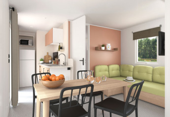 Lichte woonkamer en keuken in het Stacaravan Confort PLUS chalet met eettafel en groene zetel.