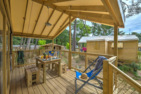 Boomhut Cosyflower met veranda en houten meubels bij Flower Camping Au Bois Des Biches in Frankrijk.