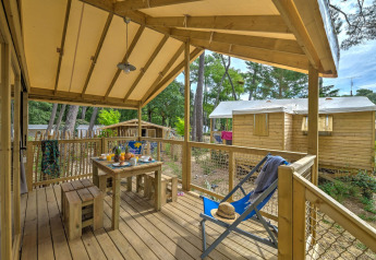 Træhytte Cosyflower med overdækket terrasse og spisebord på Flower Camping Au Bois Des Biches i Frankrig.