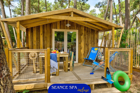 Gemütliche Sweetflower Lodge aus Holz mit Terrasse, Stühlen und sommerlichen Accessoires im Wald.