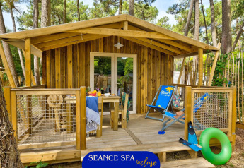 Sweetflower Lodge in legno con veranda accogliente, sdraio e ambiente boschivo estivo intorno.