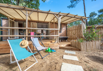 Stacaravan Garden Chalet mit Holzterrasse, Liegestühlen und Naturgarten in entspannter Umgebung.