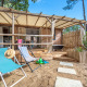 Stacaravan Garden chalet met houten terras, strandstoelen en zandomgeving, omringd door natuur.