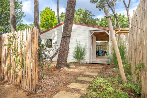 Sendero de piedras hacia la cabaña Cottage Garden, rodeada de valla de madera, árboles y vegetación verde.