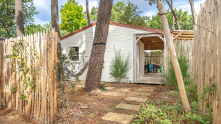 Pfad mit Steinplatten führt zur Cottage Garden-Hütte, umgeben von Holzzaun und Bäumen im Grünen.