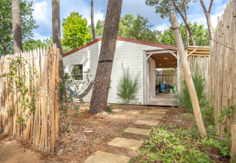 Pad van stenen leidt naar de Cottage Garden-hut, omringd door houten hek, bomen en groene beplanting.