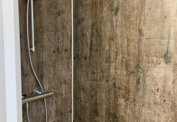 Ducha con paredes efecto madera en una cabaña en Holiday park De Witte Berg, Países Bajos.