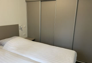 Chambre moderne avec lit double et armoire coulissante au Wood Cottage du parc De Witte Berg.