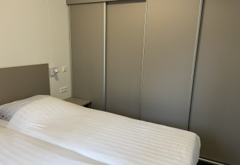 Modern bedroom with a double bed and sliding wardrobe in Wood Cottage at Holiday park De Witte Berg.