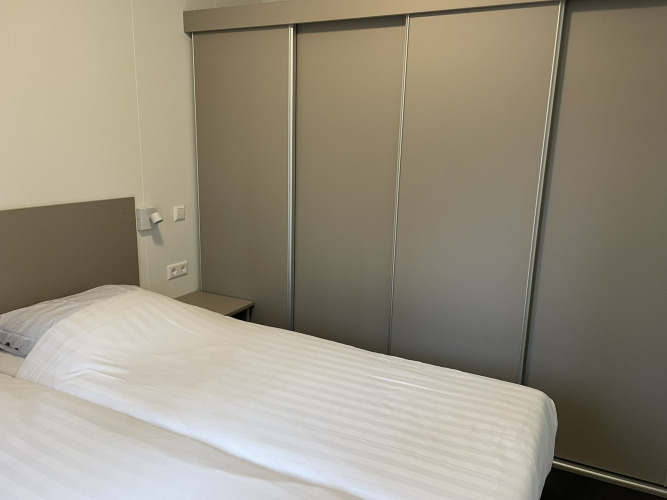 Moderne slaapkamer met dubbel bed en schuifdeurkasten in Wood Cottage in vakantiepark De Witte Berg.