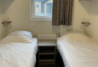 Chambre avec deux lits simples, table et fenêtre au Wood Cottage, Holiday park De Witte Berg, Pays-Bas.