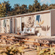 Moderne glamping-accommodatie met houten terras, buitenbank en planten in een bosrijke omgeving.