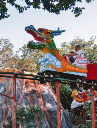Personas montando una montaña rusa con tema de dragón rodeada de naturaleza cerca de Funtana, Istria, Croacia.