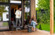 Twee mensen ontspannen op een houten terras bij Sunlodge in Holiday Park 't Rheezerwold, Nederland.